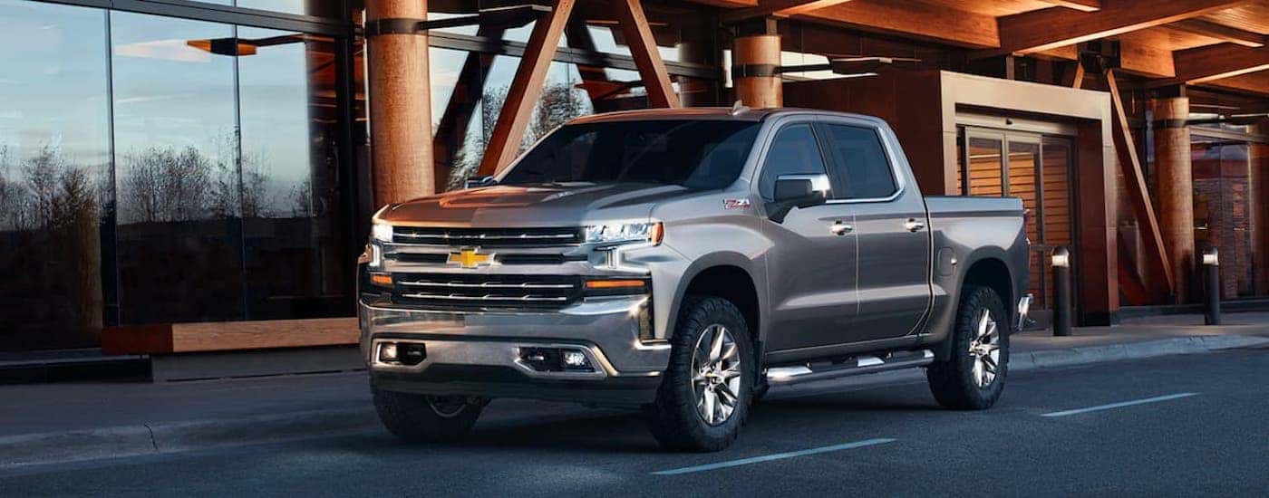 A silver 2021 Chevy Silverado Z71 is shown from the front at an angle while driving down a city street.