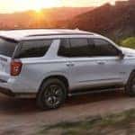 A white 2022 Chevy Tahoe is shown from the side while driving on a dirt road after leaving a Schenectady Chevy dealer.