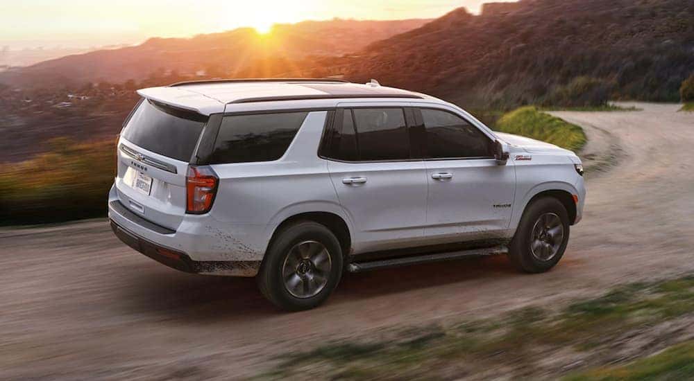 A white 2022 Chevy Tahoe is shown from the side while driving on a dirt road after leaving a Schenectady Chevy dealer.