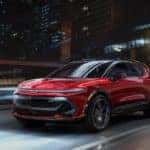 A red 2024 Chevrolet Equinox EV is shown from the front at an angle after leaving an Albany electric car dealer.