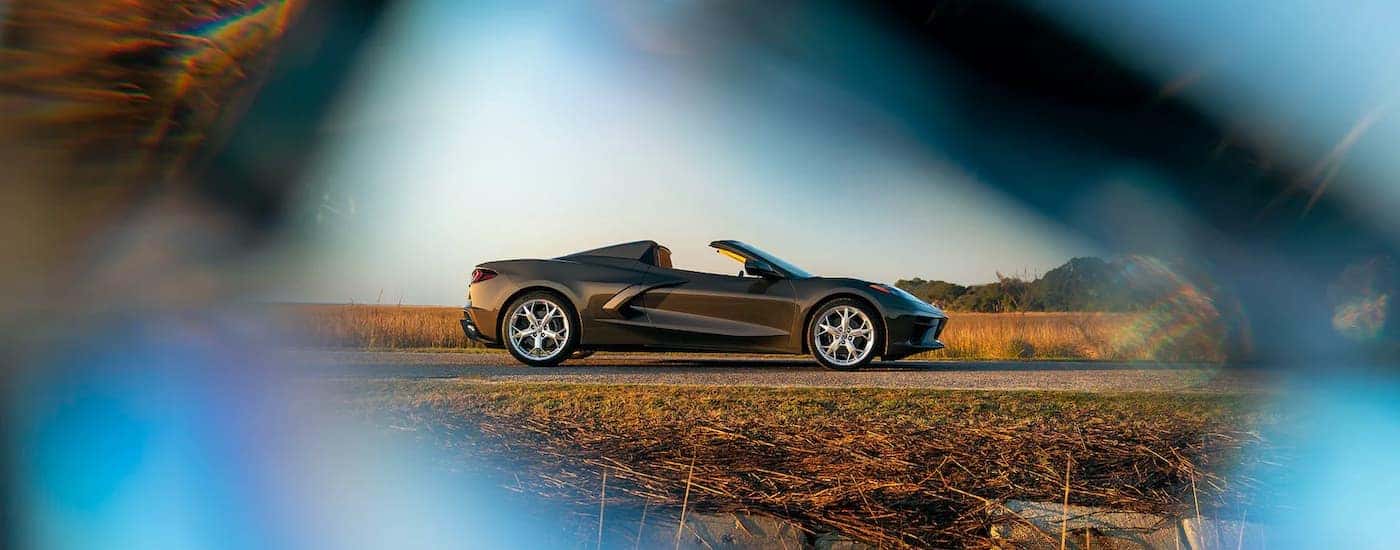 A bronze 2021 Chevy Corvette is shown from the side parked near a field of dry grass.