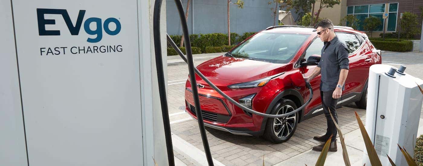 A red 2022 Chevy Bolt EUV is shown fast charging at an EVgo station.