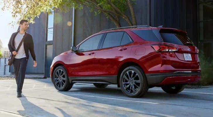 A person is shown walking past a red 2022 Chevy Equinox RS.
