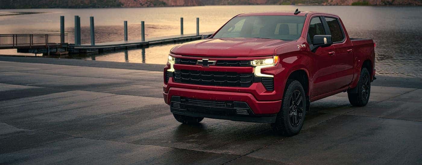 A red 2022 Chevy Silverado 1500 Z71 is shown parked in front of a lake after leaving a Chevy dealer in Saratoga Springs.