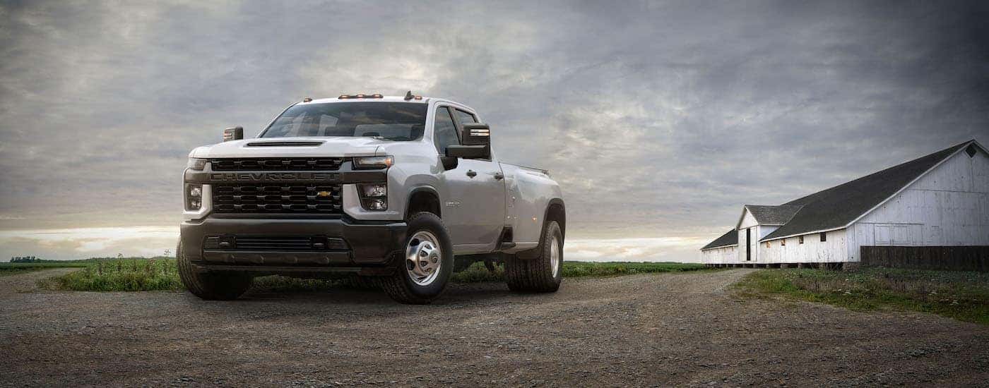 A grey 2020 Chevy Silverado 3500 HD is shown from the front at an angle while parked on a farm.