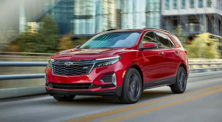 A red 2022 Chevy Equinox RS is shown driving on a city street after leaving a NY Chevy Equinox dealer.