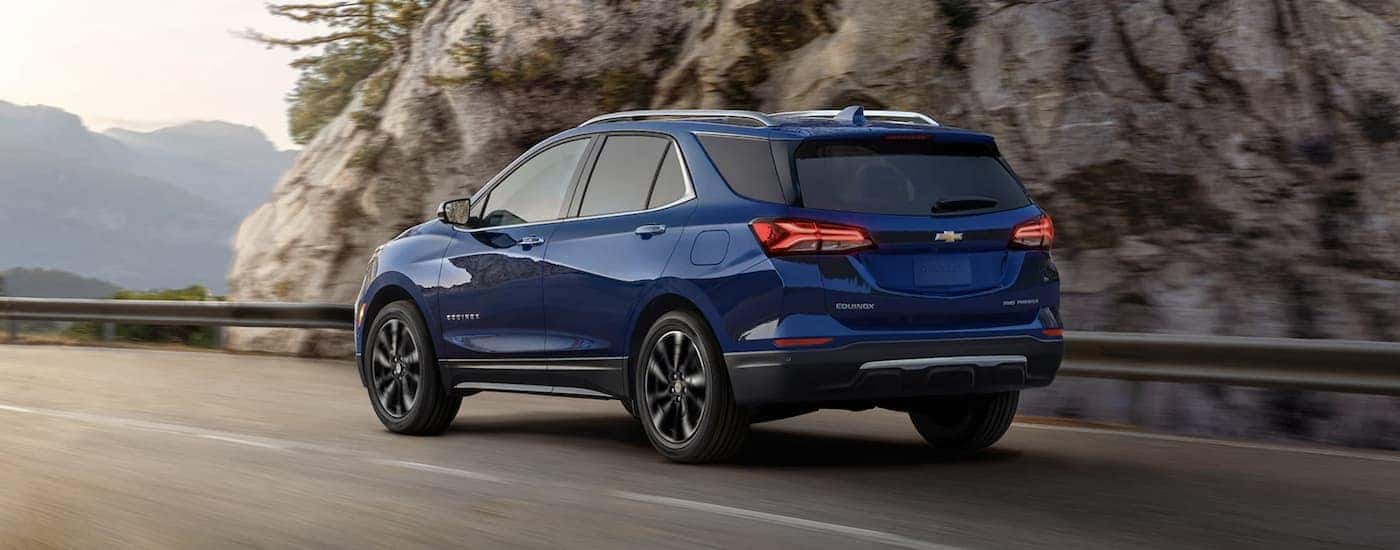 A blue 2022 Chevy Equinox is shown from the rear driving on an open road.