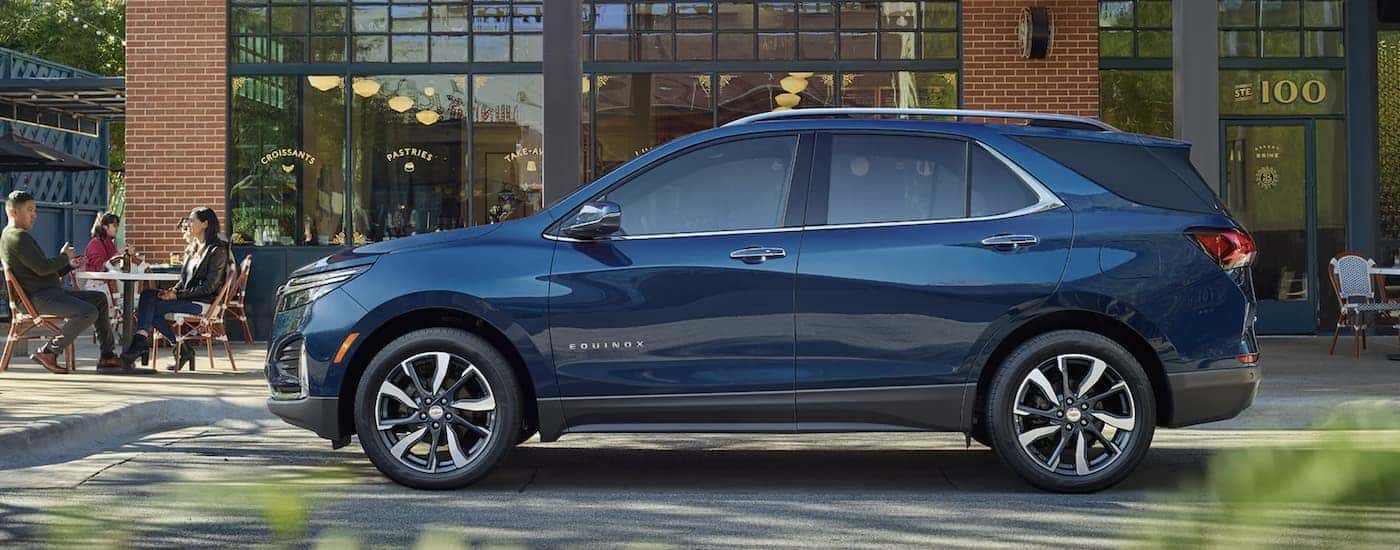 A blue 2022 Chevy Equinox is shown from the side parked in front of a building.