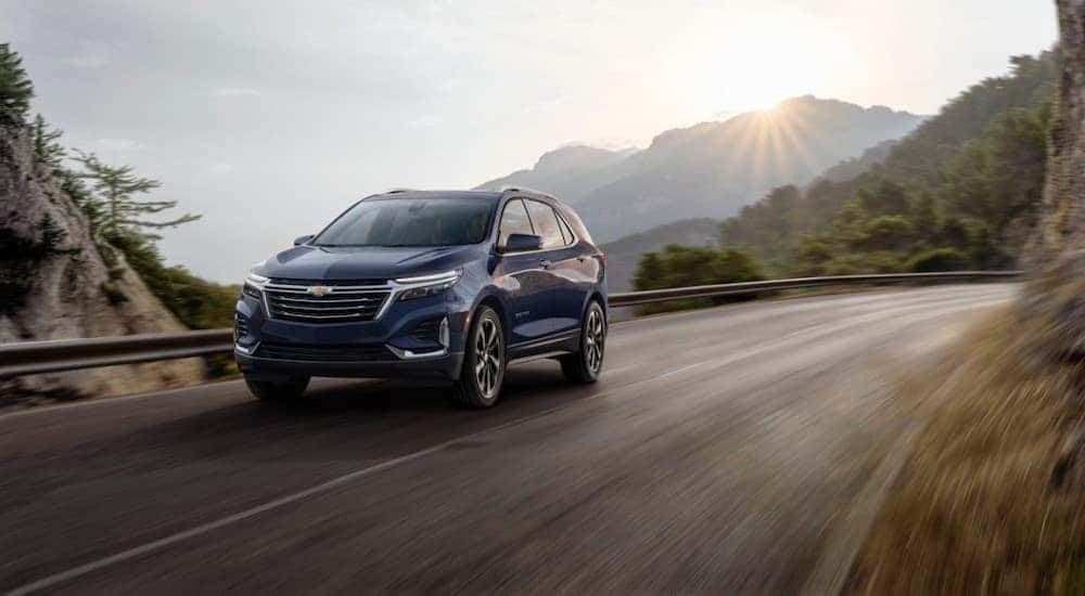 A blue 2022 Chevy Equinox is shown from the front at an angle while driving on a mountain road.