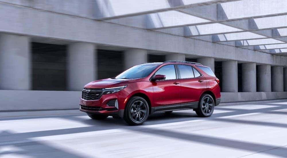 A red 2022 Chevy Equinox RS is shown from th front at an angle on a highway after leaving an Albany Equinox dealer.