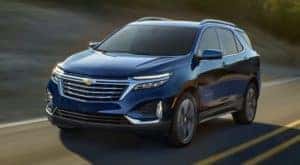 A blue 2022 Chevy Equinox is shown from the front driving on an open road.
