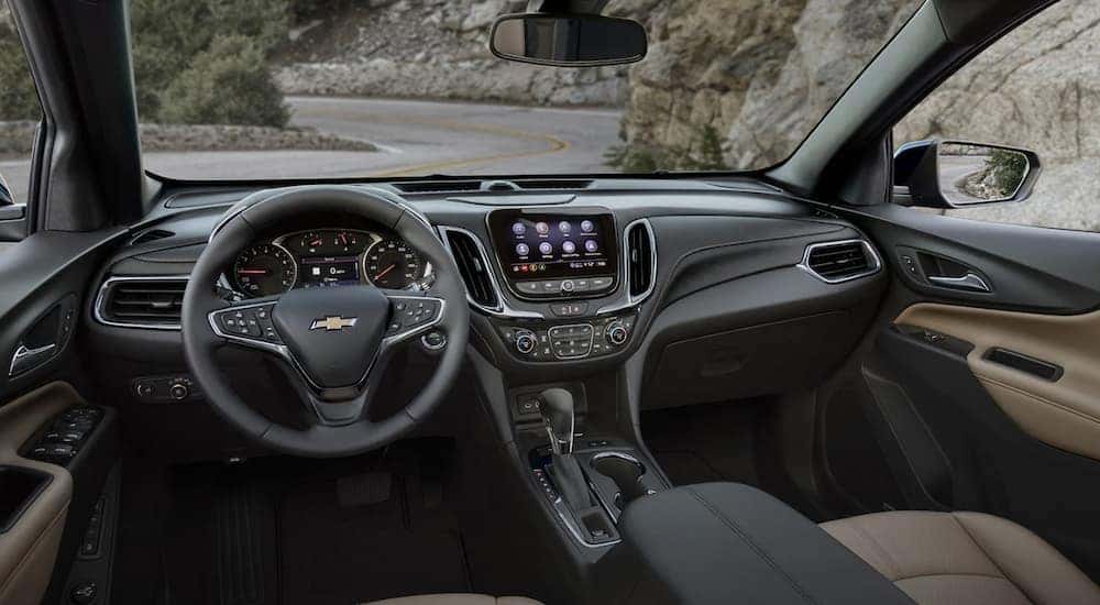 The black interior of a 2022 Chevy Equinox shows the steering wheel and infotainment screen.