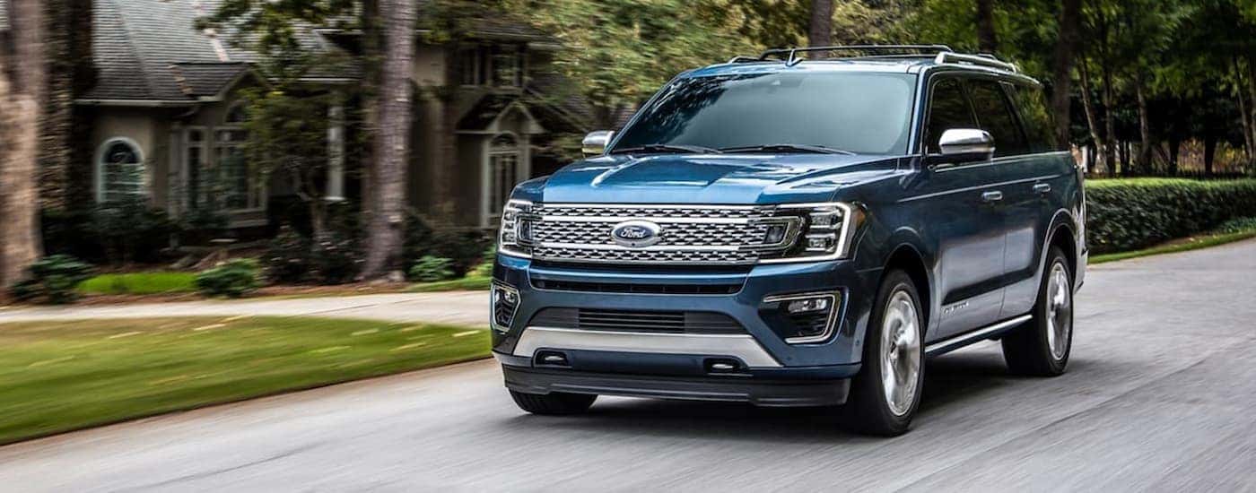 A blue 2020 Ford Expedition is shown driving through a neighborhood.