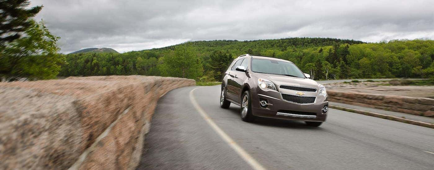 A tan 2012 Chevy Equinox LTZ is shown driving on an open road.