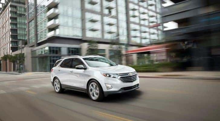 A popular Chevy Equinox for sale, a white 2019 Chevy Equinox, is shown driving on a city street.
