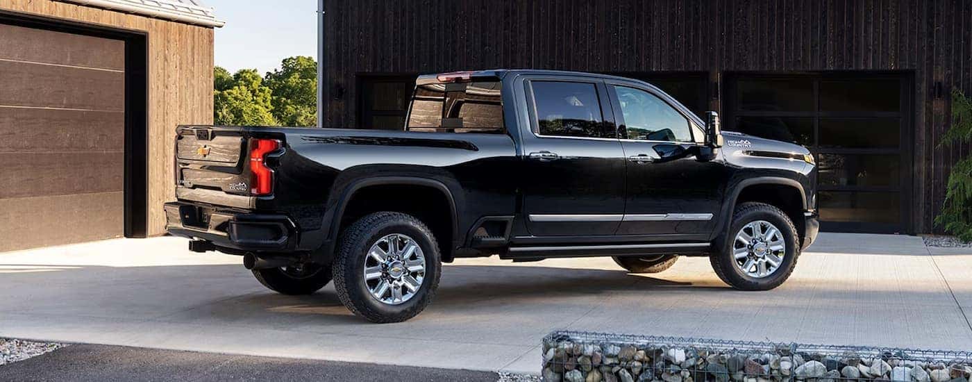 A black 2024 Chevy Silverado 2500HD High Country is shown from the side parked in a driveway.