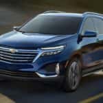 A blue 2022 Chevy Equinox is shown driving on an open road.