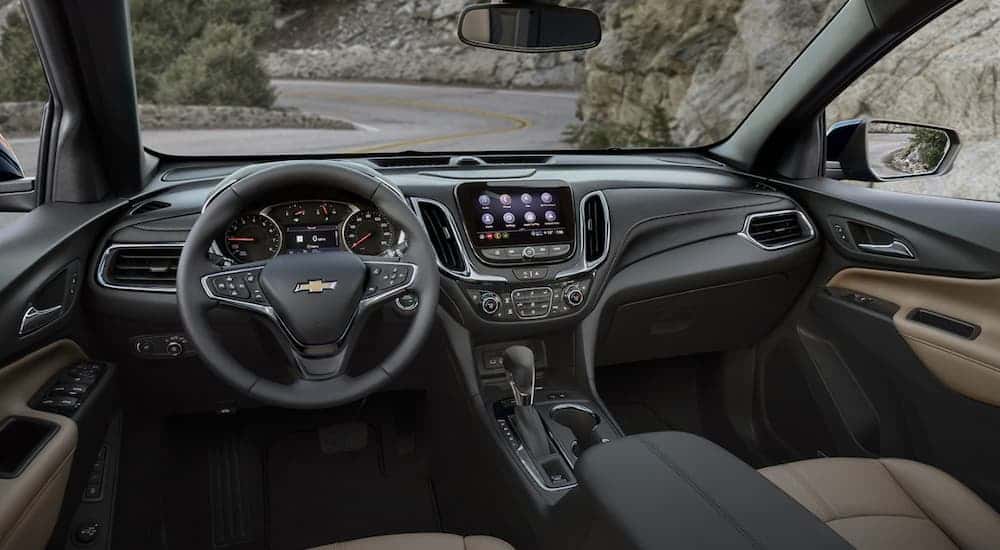 The black interior of a 2022 Chevy Equinox shows the steering wheel and infotainment screen. 