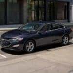 A grey 2022 Chevy Malibu is shown parked on the side of a city street.