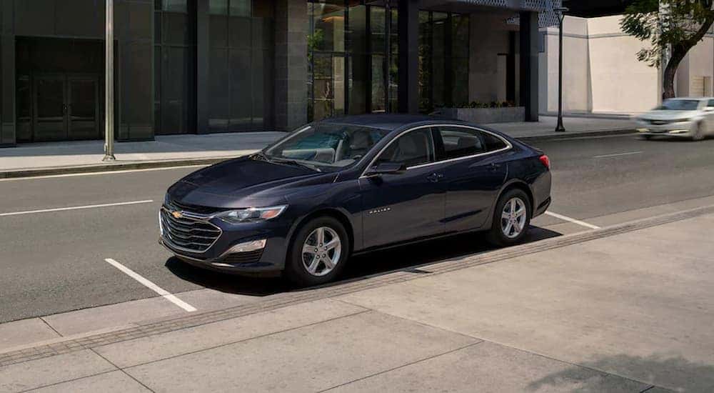 A grey 2022 Chevy Malibu is shown parked on the side of a city street.