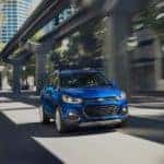 A blue 2021 Chevy Trax is shown driving on a city street.