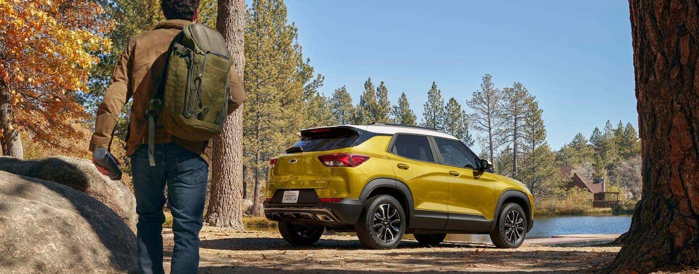 A yellow 2023 Chevy Trailblazer is shown parked near a lakeside hiking trail.