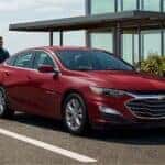 A red 2023 Chevy Malibu is shown parked on a driveway after visiting a Saratoga, NY Malibu dealer.