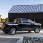 A black 2024 Chevy Silverado 2500 HD is shown from the side in a driveway.