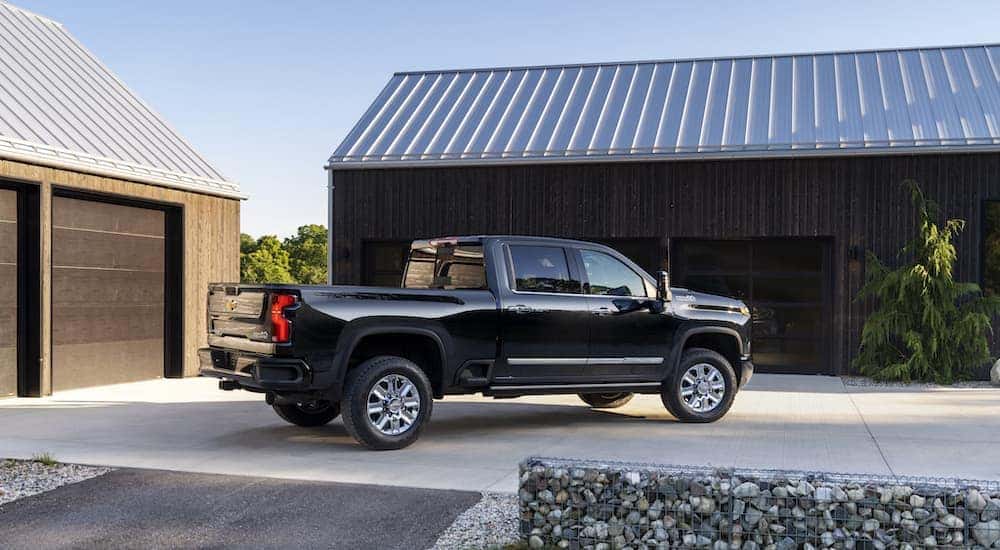 A black 2024 Chevy Silverado 2500 HD is shown from the side in a driveway.