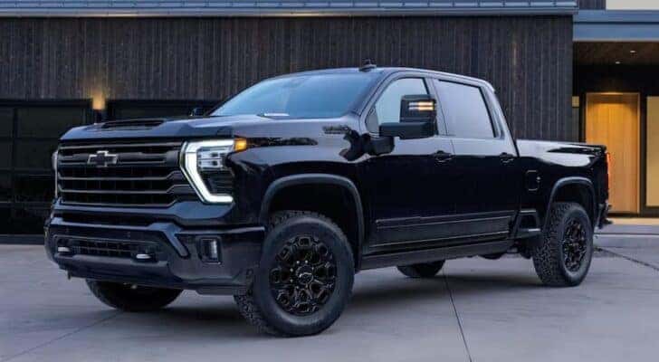 A black 2024 Chevy Silverado 3500 HD is shown at an angle parked in front of a building.