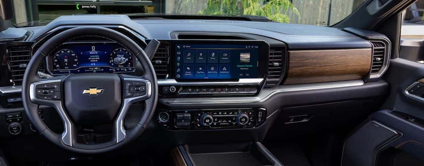 The black and brown interior of a 2024 Chevy Silverado 3500 HD shows the steering wheel and infotainment screen.