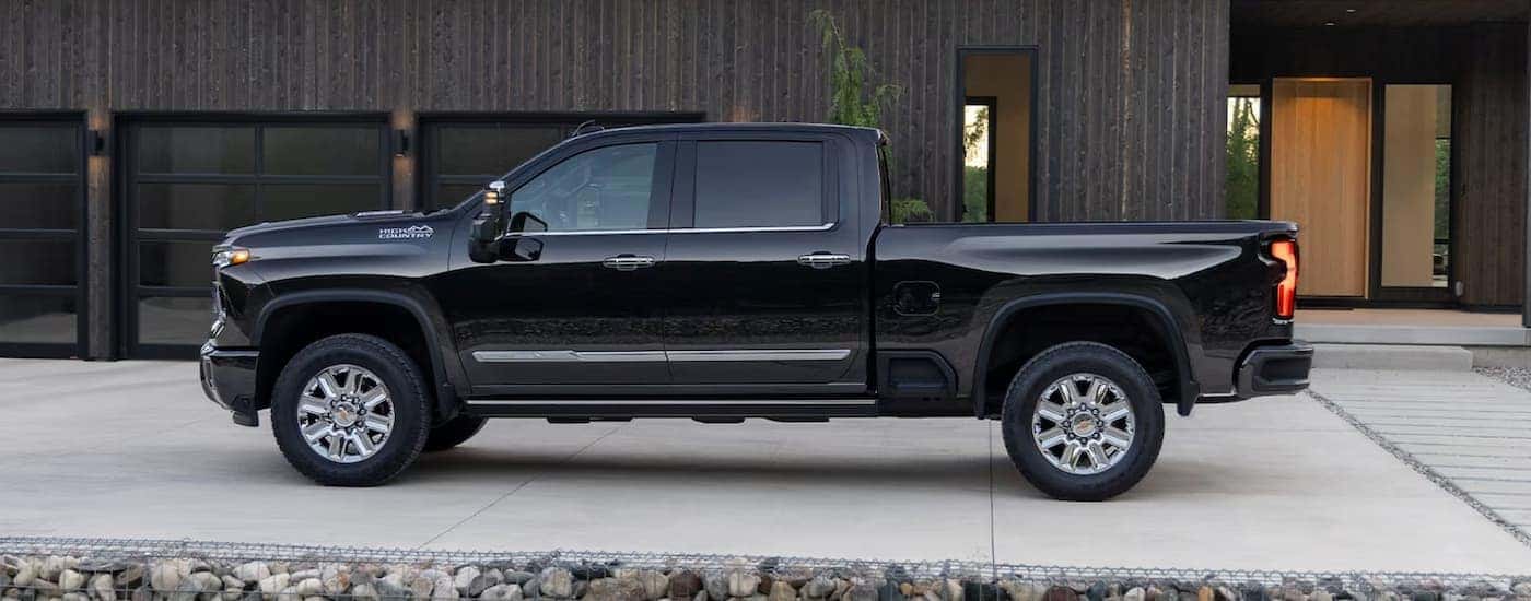 A black 2024 Chevy Silverado 3500 HD for sale is shown from the side parked in front of a building.