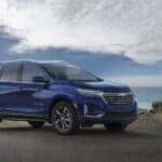 A blue 2022 Chevy Equinox Premier is shown from the side while parked on the coast.