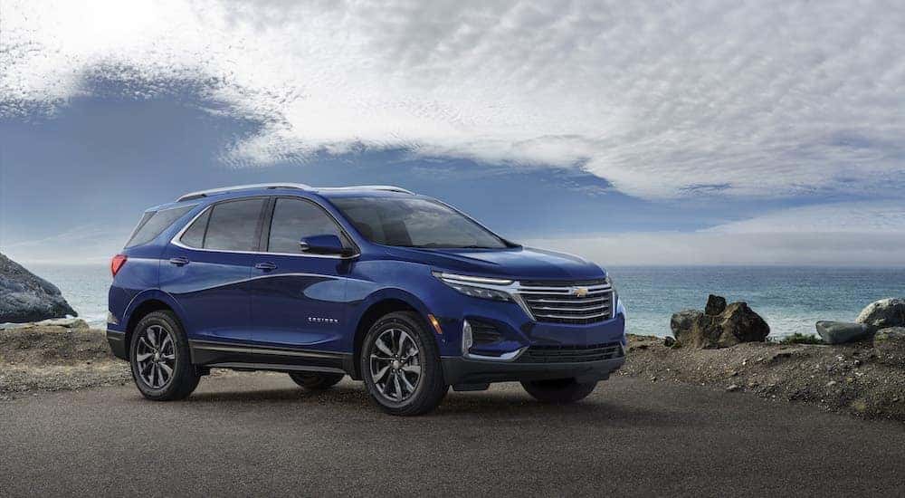 A blue 2022 Chevy Equinox Premier is shown from the side while parked on the coast.