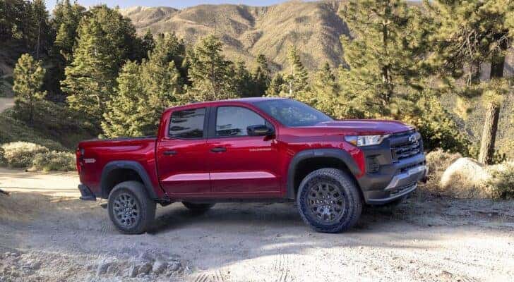 A red 2023 Chevy Colorado Trail Boss is shown driving on a dirt road after leaving a Chevy dealer near Catskill.