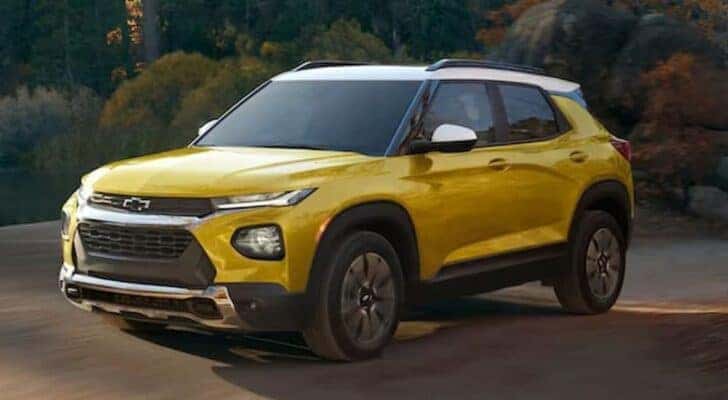 A yellow 2023 Chevy Trailblazer is shown driving off-road after visiting used cars for sale near Colonie, NY.