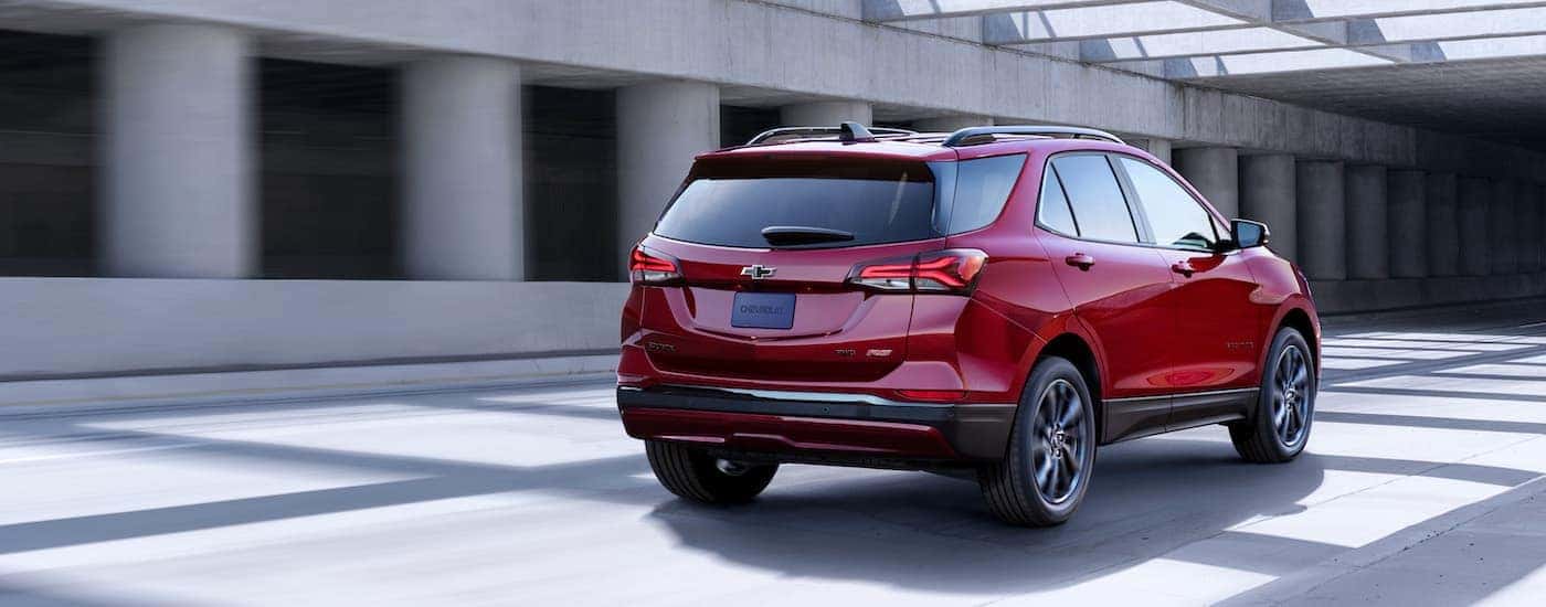A red 2022 Chevy Equinox RS is shown from the rear at an angle after leaving a Chevy dealer near Herkimer.