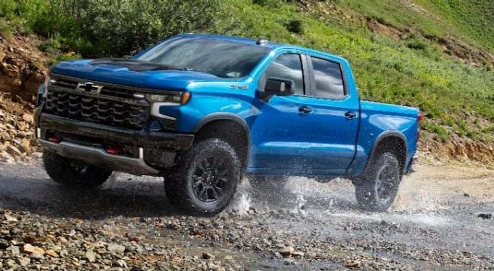 A blue 2024 Chevy Silverado 1500 ZR2 is shown driving off-road after viewing a Chevy Silverado for sale.