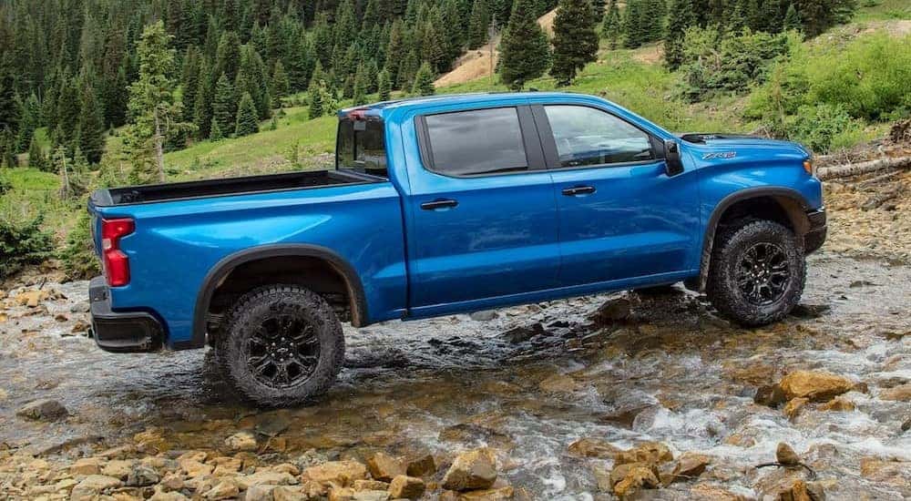A blue 2024 Chevy Silverado 1500 ZR2 is shown parked on wet rocks.