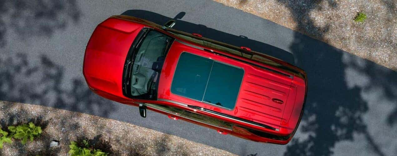 A red 2024 Chevy Traverse RS is shown from above on a paved road.