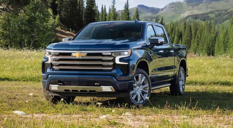 A blue 2023 Chevy silverado 1500 High Country is shown parked on grass after viewing used trucks for sale near Colonie.