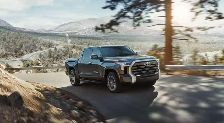 A black 2023 Toyota Tundra is shown driving on a road.