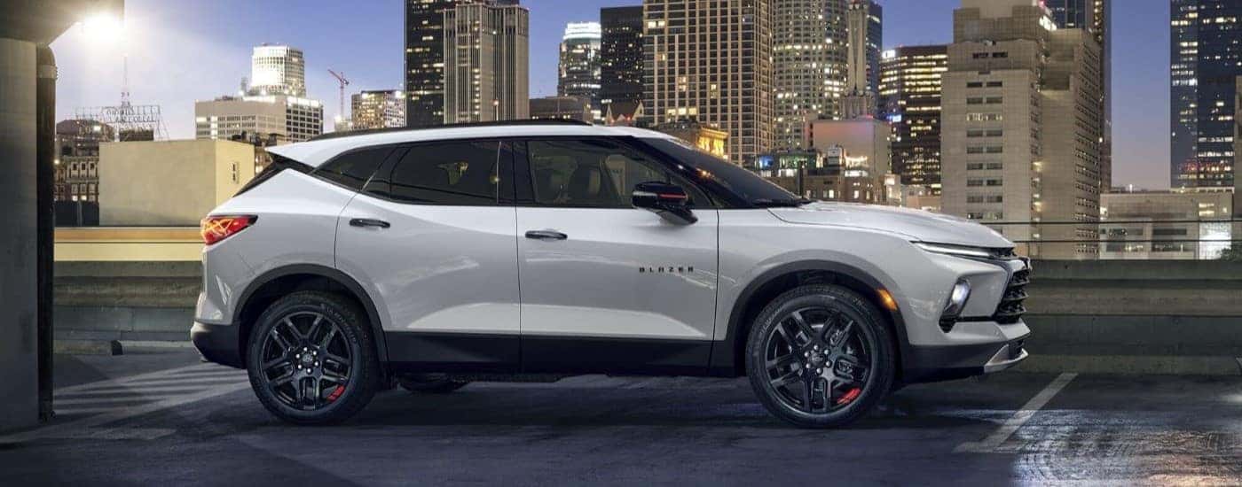 A white 2024 Chevy Blazer Redline is shown from the side in front of a city skyline at night.