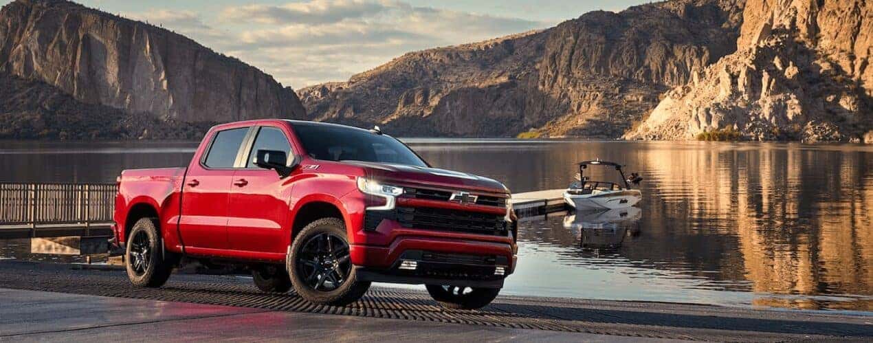 A red 2024 Chevy Silverado 1500 LTZ Z71 is shown parked next to a lake.
