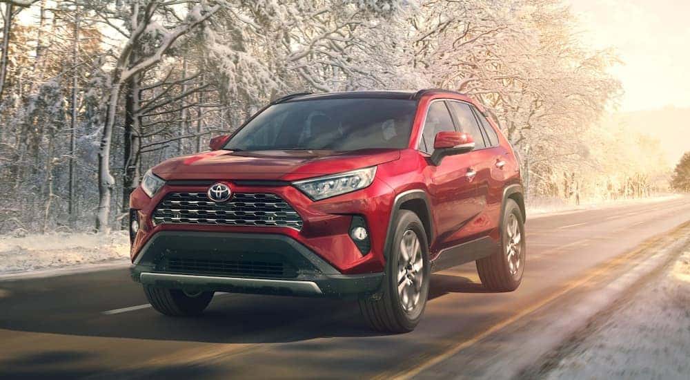 A red 2019 Toyota RAV4 is shown driving on a snowy day.
