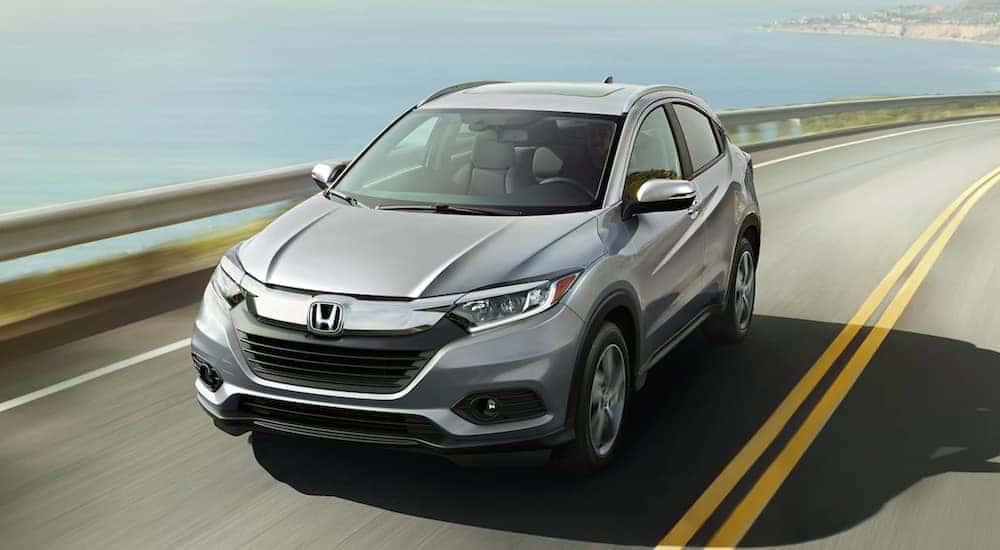 A silver 2021 Honda HR-V EX-L is shown driving on a highway.