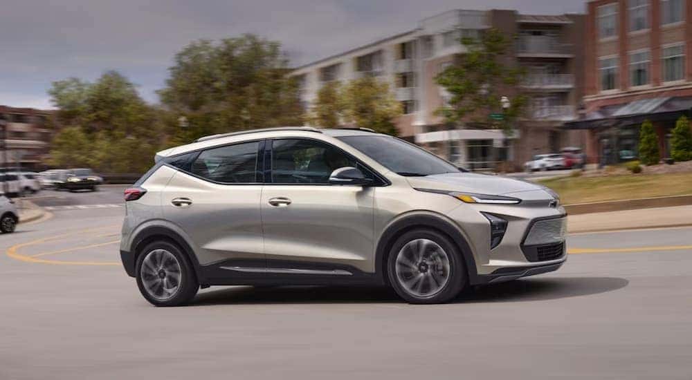 A tan 2023 Chevy Bolt EUV is shown driving on a city street.