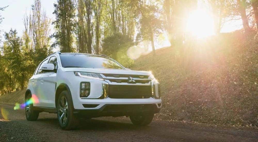 A white 2023 Mitsubishi Outlander Sport is shown driving near a forest.