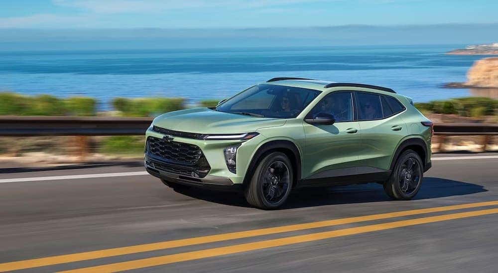 A green 2024 Chevy Trax is shown driving on a highway.