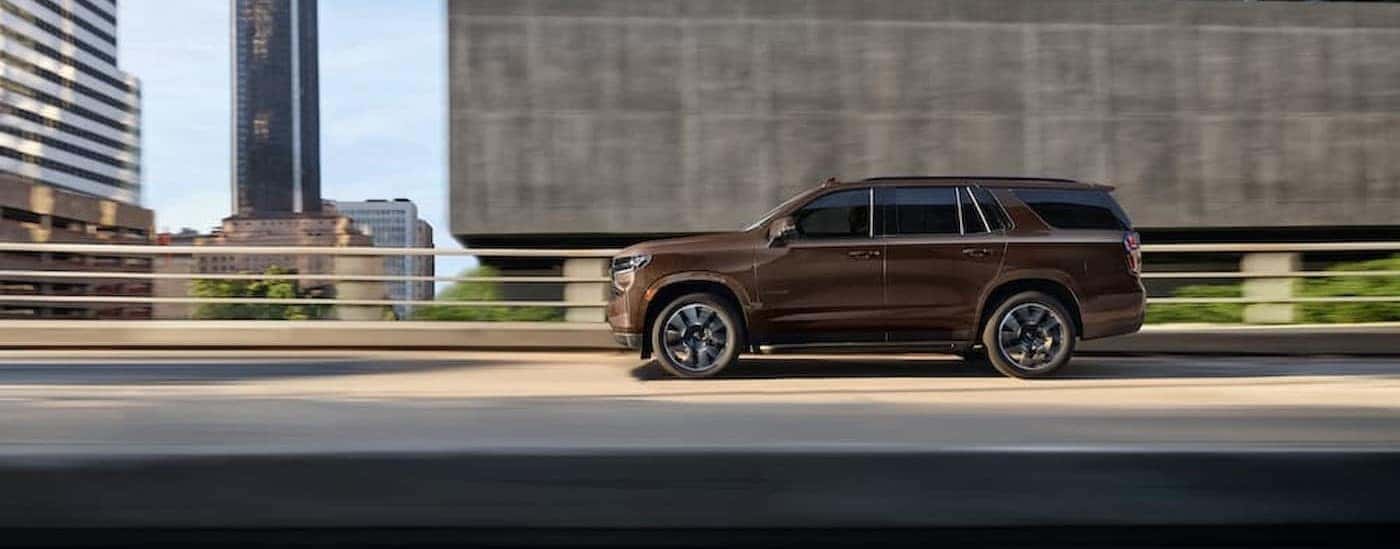 A brown 2022 Chevy Tahoe is shown driving on a bridge.
